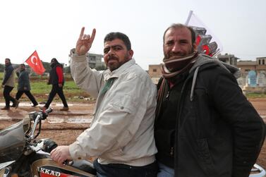 In this file photo taken on February 14, 2020, a motorcycle rider flashes the Grey Wolves gesture as people behind him march with Turkish flags during a demonstration at a Turkish military observation post in the town of Binnish in Syria’s north-western province of Idlib, near the Syria-Turkey border. AFP