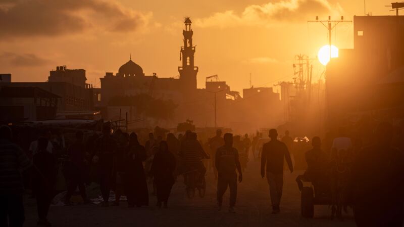 Palestinians walk at sunset among destroyed buildings at Khan Younis refugee camp, in the south of the Gaza Strip. EPA