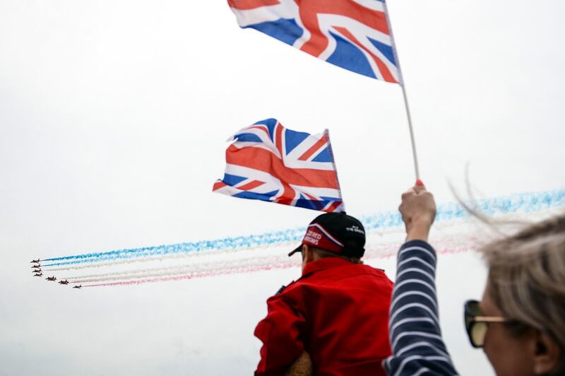 Spectators wave British Union flags, also known as a Union Jacks, as they watch a fly past as part of the the D-Day service on Southsea Common, in Portsmouth. Bloomberg