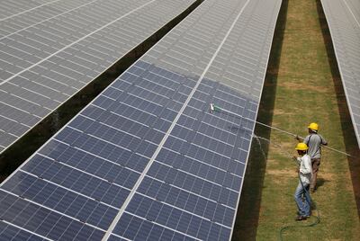 Workers clean solar panels at a power plant in Gujarat, India. Increasing use of renewable electricity sources has improved district cooling's sustainability. Reuters