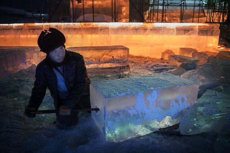 A Chinese labourer cuts into a large ice block to place lights as he works with others to finish large ice sculptures in preparation for the Harbin Ice and Snow Festival in Harbin, China. Getty Images