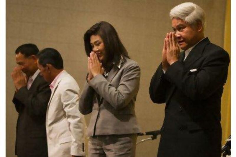 Yingluck Shinawatra gives the traditional Thai greeting alongside her new coalition party members, the day after her Pheu Thai party won an overwhelming victory in national elections. Paula Bronstein / Getty Images