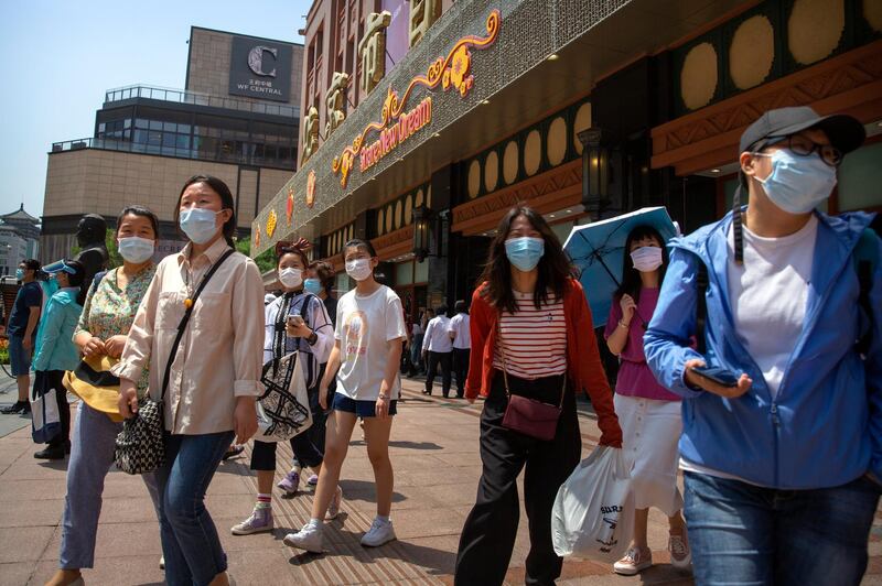 People wearing face masks to protect against the new coronavirus walk outside of a shopping mall at a pedestran shopping street in Beijing. China's capital is lowering its emergency response level to the second-lowest starting Saturday for the coronavirus pandemic. That will lift most restrictions on people traveling to Beijing from Wuhan and surrounding Hubei province, where the virus first appeared late last year. AP Photo