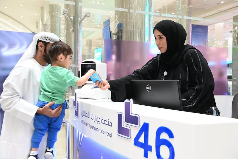 Dubai International Airport staff help a young passenger stamp his passport. Photo: General Directorate of Residency and Foreign Affairs
