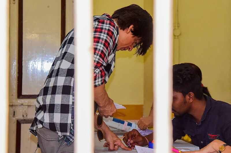 Bollywood actor Shah Rukh Khan (L) interacts with officials as he casts his vote at a polling station during the state assembly election in Mumbai on October 21, 2019.  / AFP / Sujit Jaiswal
