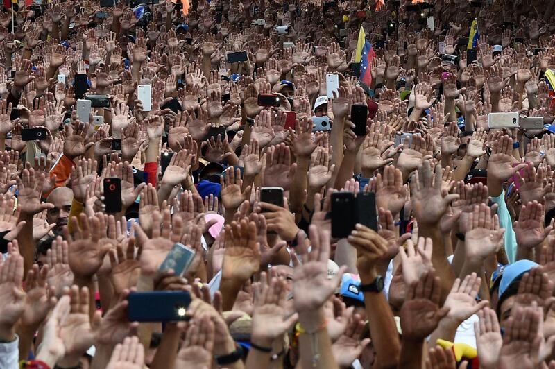 People raise their hands during a mass opposition rally against President Nicolas Maduro in Caracas. AFP