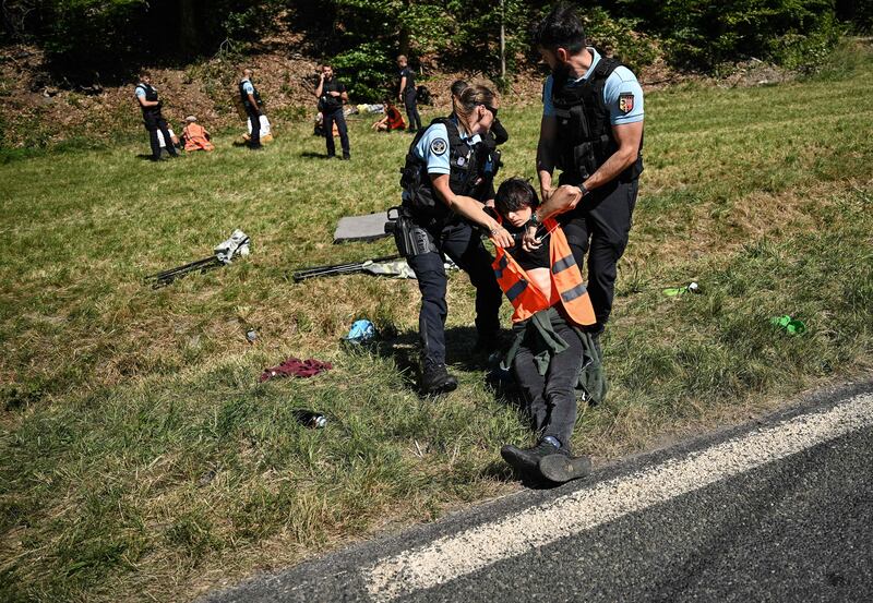 French gendarmes remove environmental protestors from the race route. AFP