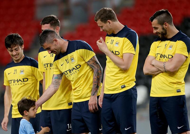 From left to right, Manchester City players David Silva, Gareth Barry (obscured), Aleksandar Kolarov greeting a young fan, Edin Dzeko and Alvaro Negredo before their training session in Abu Dhabi on Wednesday. Satish Kumar / The National / May 14, 2014