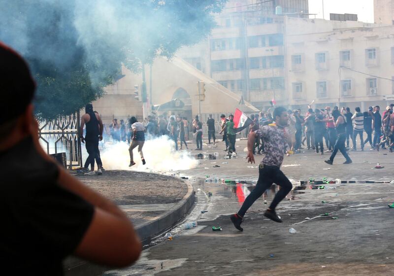 Iraqi protesters run for cover amid tear gas fired by policemen during a demonstration at Tahrir Square, central Baghdad.  EPA