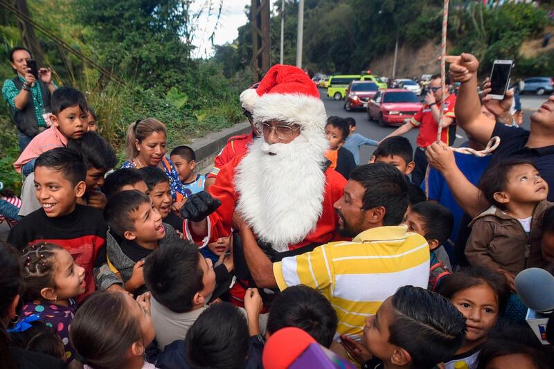 Guatemalan municipal firefighter Hector Chacon, dressed as Santa Claus, arrives to deliver presents to children after going down a cable from a bridge in Guatemala City.  AFP