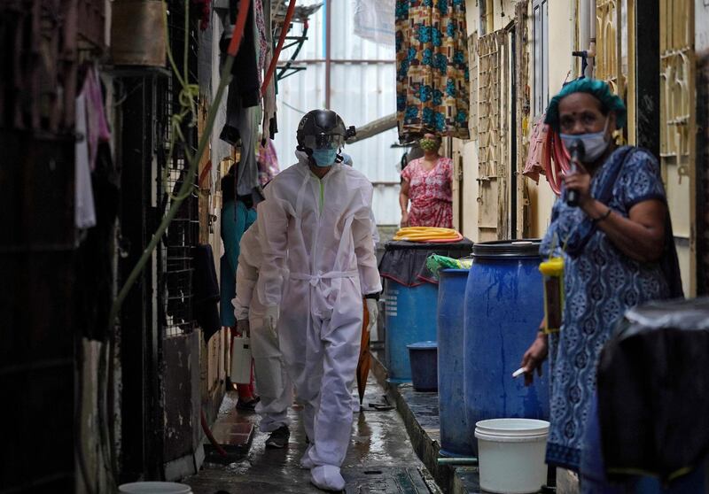 FILE PHOTO: A worker from Bharatiya Jain Sanghatana, a non-governmental organization, wearing a "Smart Helmet", a portable thermoscanner that can measure the temperature of people at a distance, walks in an alley to screen the residents during a check-up campaign for the coronavirus disease (COVID-19) in a slum Mumbai, India, July 23, 2020.  REUTERS/Hemanshi Kamani - RC2ZYH93CJLN/File Photo