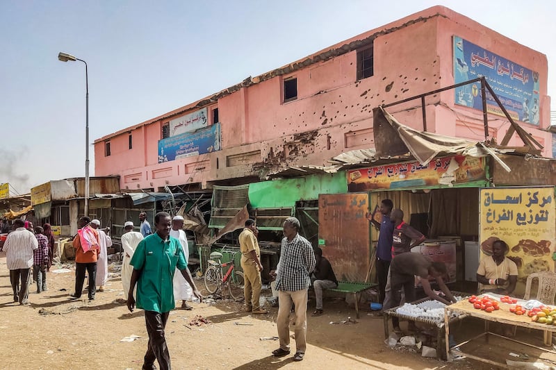 People walk past a medical centre riddled with bullet holes in southern Khartoum, where the Sudanese army is battling the paramilitary Rapid Support Forces. AFP