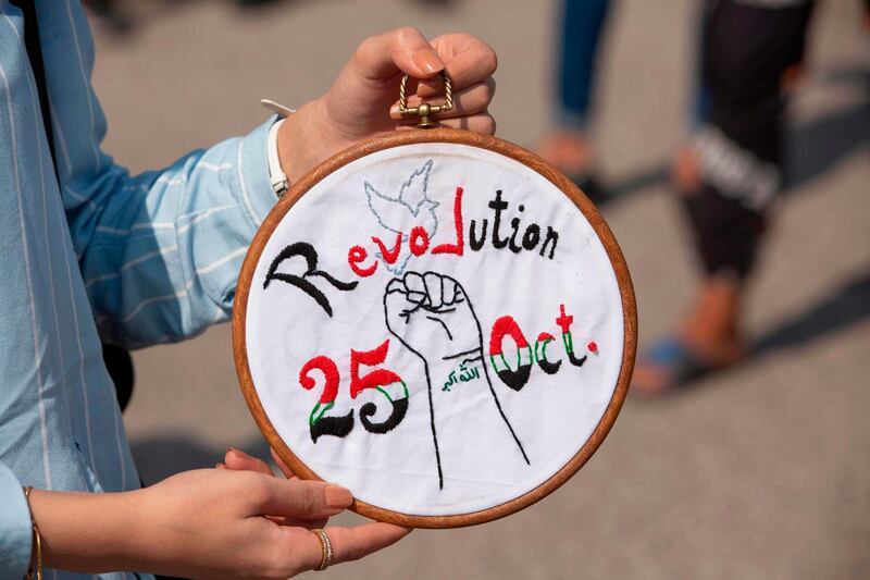 An Iraqi demonstrator displays an embroidery as protesters gather near the local administration building in the southern city of Basra, to mark the first anniversary of a massive anti-government movement demanding the ouster of the entire ruling class accused of corruption.  AFP