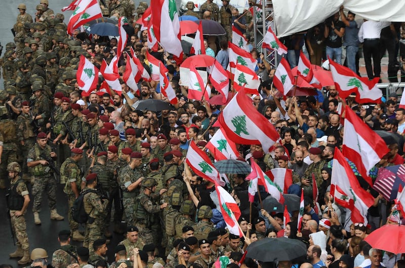 Anti-government protester wave national flags as Lebanese army soldiers surround them in the area of Jal al-Dib in the northern outskirts of the Lebanese capital Beirut, on October 23, 2019.  A week of unprecedented Lebanese street protests against the political class showed no signs of abating today, despite the army moving to reopen key roads.
Protests sparked on October 17 by a proposed tax on WhatsApp and other messaging apps have morphed into an unprecedented cross-sectarian street mobilisation against the political class. / AFP / Anwar AMRO

