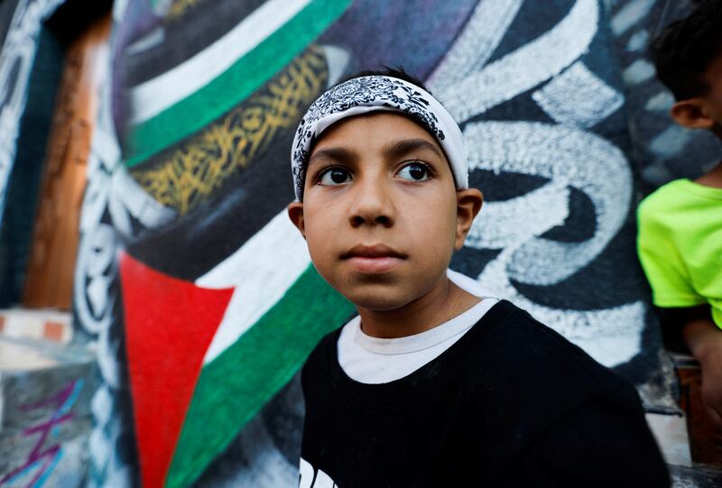 A Palestinian boy participates in a breakdance performance on a street in the Nuseirat refugee camp.