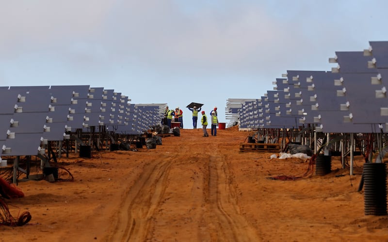 Workers install solar panels at a photovoltaic solar park situated on the outskirts of the coastal town of Lamberts Bay, South Africa. AP