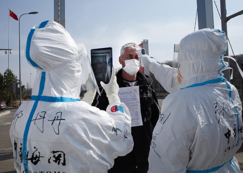 Staff check the temperature of a driver at a customs checkpoint on the border with Russia at Suifenhe, in China's northeast Heilongjiang province.  AFP