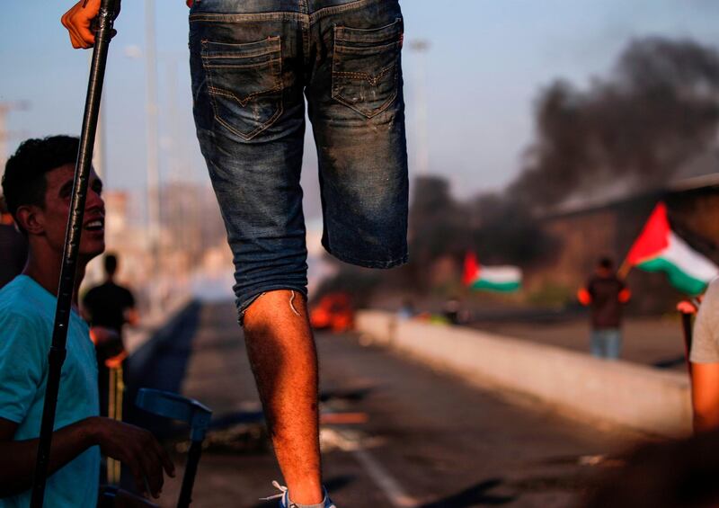 An amputee protester stands with a crutch on a concrete barricade during clashes with Israeli forces in the northern Gaza Strip. AFP