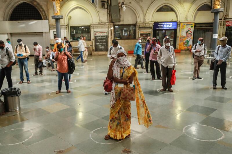 Commuters stand inside circles to maintain social distancing as they wait to board a train at a railway station after some restrictions were lifted in Mumbai. Reuters