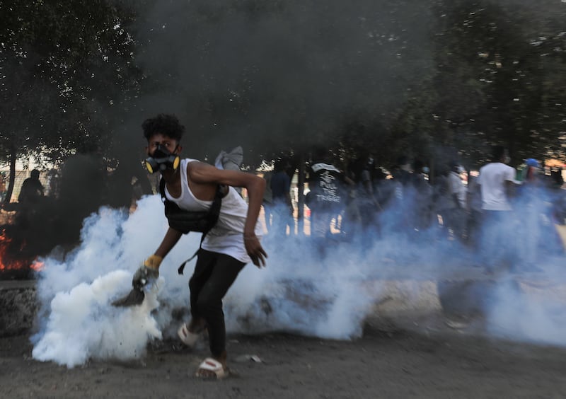 A Sudanese protester attempts to throw back a tear gas canister during clashes with security forces at an anti-coup protest, in Khartoum, Sudan, 09 January 2022.  Security forces fired tear gas to disperse protesters gathering in Khartoum and attempting to march towards the presidential palace, as part of the continuing protesting movement against a military coup in October 2021.  The protest was organized a day after the UN envoy for Sudan said the international group will invite different parties for talks in Sudan to end the crisis.  EPA