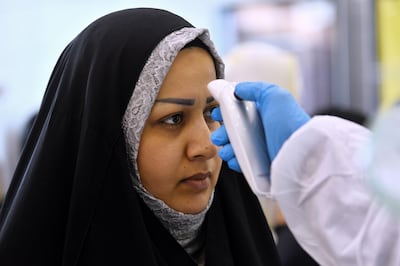 The body temperature of an Iraqi woman returning from Iran is measured upon her arrival at the Najaf International Airport on February 21, 2020, after Iran announced cases of coronavirus infections in the Islamic republic.  / AFP / Haidar HAMDANI
