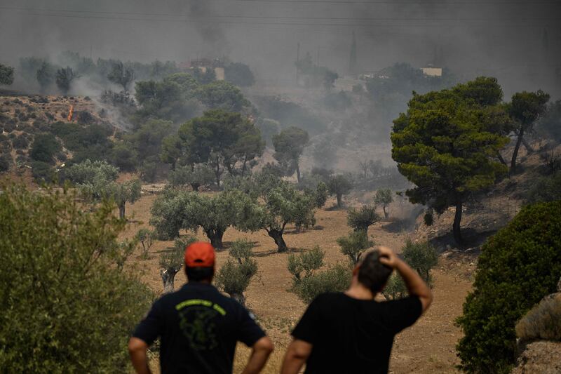 A firefighter and a resident watch a wildfire near Nea Peramos, west of Athens, Greece. AFP