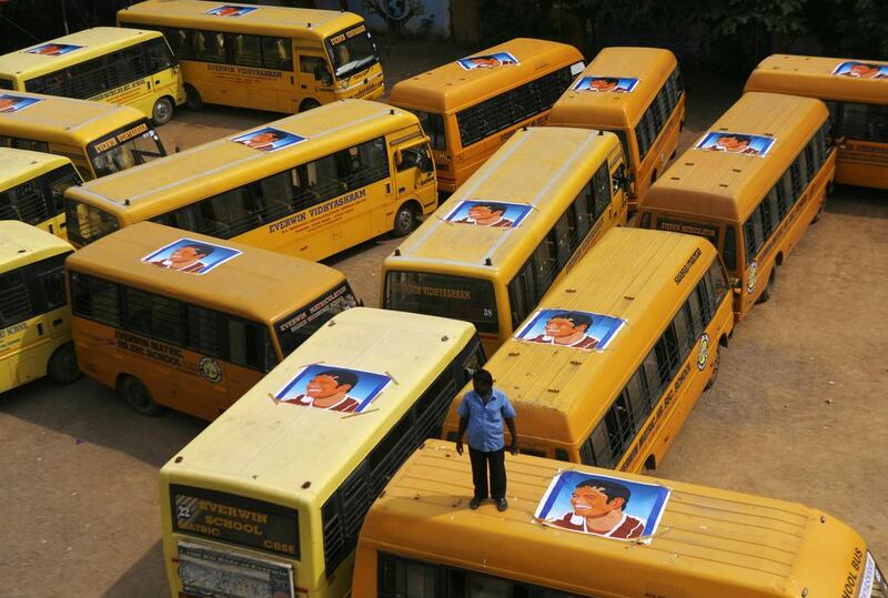 A man stands atop the poster-adorned school buses that brought the school children to the gathering in Chennai, India on Thursday. Arun Sankar K / AP