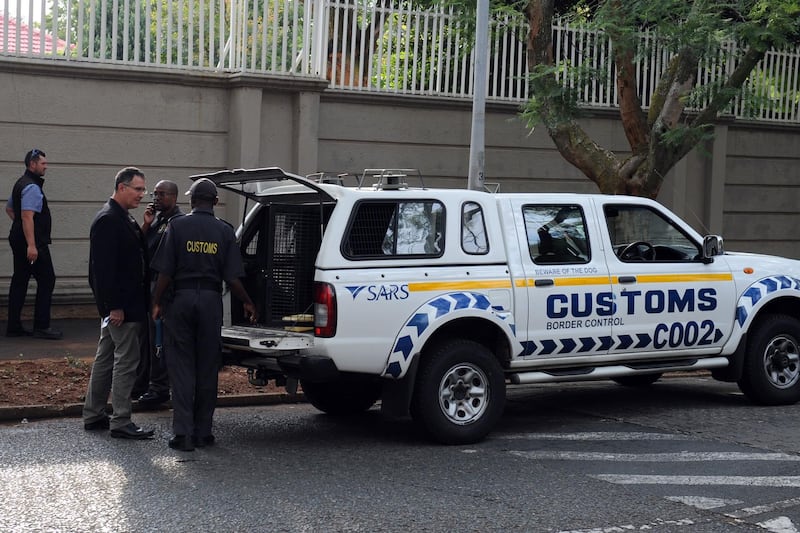 Members of the South African Asset Forfeiture Unit and other law enforcement agencies arrive to search the Gupta family compound on April 16, 2018 in Johannesburg. 
South African officials on April 16 raided a Johannesburg property belonging to the Guptas, the wealthy business family at the heart of graft allegations against former president Jacob Zuma. The Hawks police investigative unit and the tax service descended on the Guptas' heavily protected compound in the upmarket suburb of Saxonwold.
 / AFP PHOTO / STRINGER
