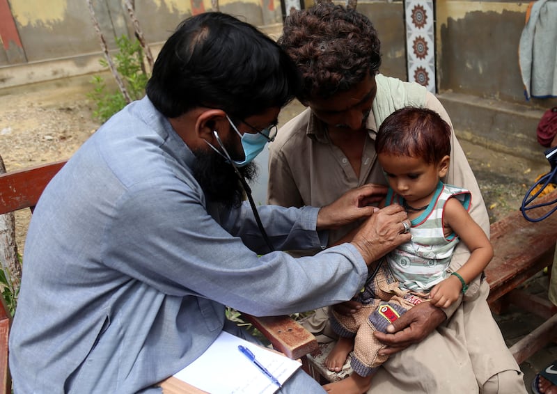 A doctor checks a child at a makeshift medical camp in Sanghar District, Sindh Province. EPA