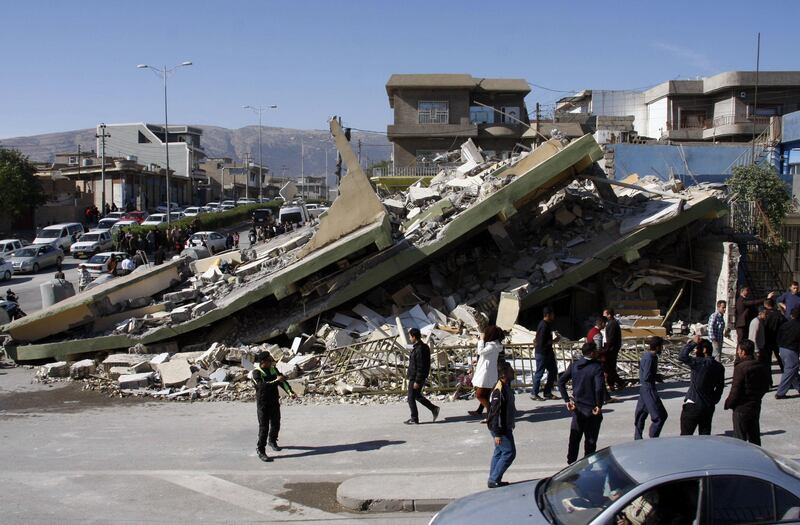 People gather around a levelled building in the mountainous town of Darbandikhan in Iraqi Kurdistan on November 13, 2017, following a 7.3-magnitude quake that hit the Iraq-Iran border area. / AFP PHOTO / SHWAN MOHAMMED