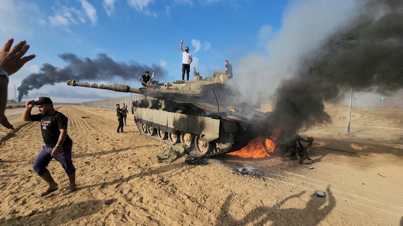 Palestinians celebrate by a destroyed Israeli tank at the Gaza Strip border fence, east of Khan Younis. AP 