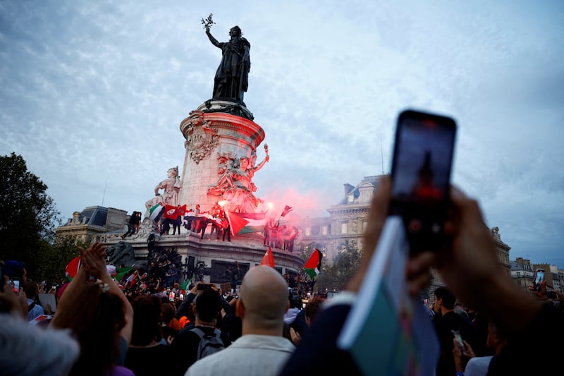 Protestors hold Palestinian flags and red flares during a demonstration at Place de la Republique in Paris. Reuters