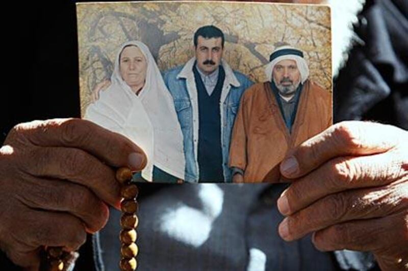The father of Mahmoud al Mabhouh holds up a family photo showing al Mabhouh, centre, at their home in the Jebaliya refugee camp, northern Gaza.