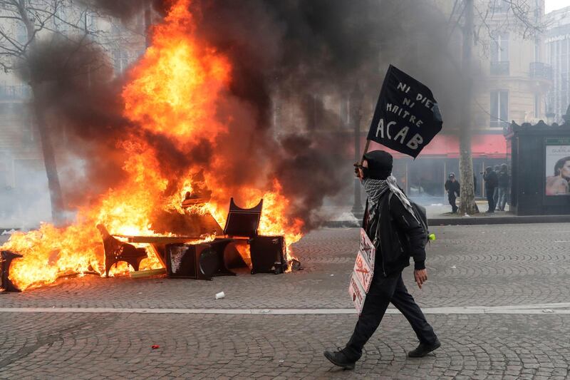A protester walks past a burning barricade on the Champs-Elysees in Paris on March 16, 2019. AFP