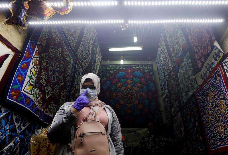 A woman wearing a protective face mask is pictured next to traditional Ramadan products which are displayed for sale at Al Khayamia street in old Cairo. Reuters