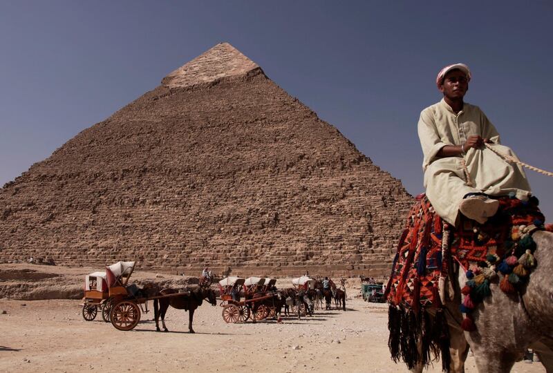 FILE - In this Oct. 11, 2012 file photo, an Egyptian camel owner waits for customers to take a ride, in front of the Khafre pyramid, near Cairo, Egypt. The Antiquities Ministry said in a statement Wednesday Oct. 31, 2018, that the second of Egypt's three famed pyramids of Giza will open to tourists this week after the completion of restoration work that lasted about two months. The pyramid of King Khafre, one of the three Great Pyramids gracing the Giza province south of Cairo, will be ready to receive tourists starting Thursday. (AP Photo/Nariman El-Mofty, File)