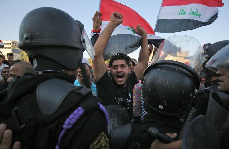 Iraqi protesters shout slogans and wave national flags during clashes at a demonstration against unemployment and a lack of basic services in the capital Baghdad's Tahrir Square. AFP
