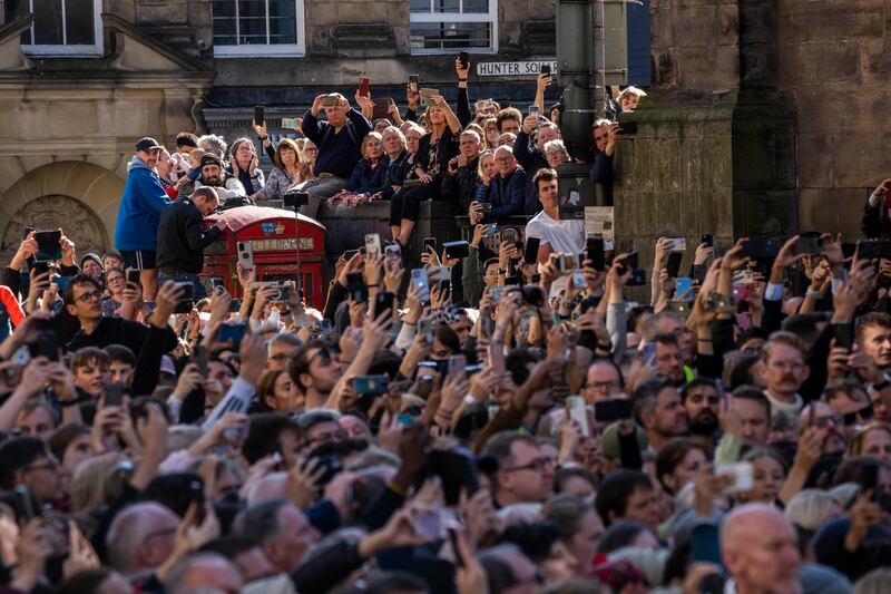 People attend the procession of Queen Elizabeth II's coffin, from the Palace of Holyroodhouse to St Giles' Cathedral, on the Royal Mile in Edinburgh, Scotland, on Monday.  AP