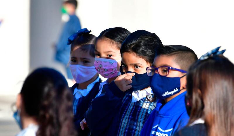 A students adjusts her facemask at St. Joseph Catholic School in La Puente, California where pre-kindergarten to Second Grade students in need of special services returned to the classroom today for in-person instruction.  The campus is the second Catholic school in Los Angeles County to receive a waiver approval to reopen as the coronavirus pandemic rages on.  The US surpassed 11 million coronavirus cases Sunday, adding one million new cases in less than a week, according to a tally by Johns Hopkins University. AFP