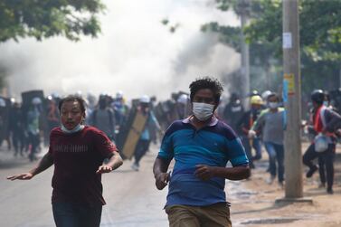 Anti-coup protesters run when police try to disperse them with tear gas in Mandalay, Myanmar. AP Photo
