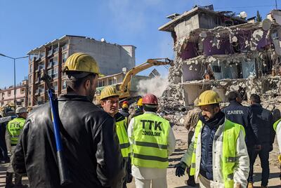 Miners wait as heavy machinery removes a section of a damaged building to allow rescuers to search for survivors in Antakya. AFP