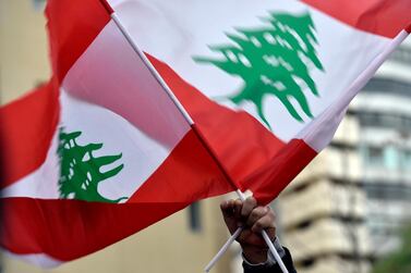 A protester waves Lebanese national flags as he takes part in a demonstration against the nomination of Hassan Diab as Prime Minister, outside his house in Beirut. EPA