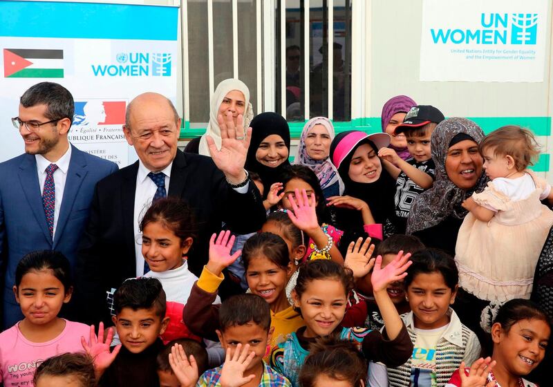 French Foreign Minister Jean Yves Le Drian (2nd-L) poses for a picture with Syrian refugees taking part in the Oasis for Women and Girls, a project launched by United Nations Entity for Gender Equality and Women’s Empowerment (UN Women), at the Azraq camp for Syrian refugees in northern Jordan on August, 2, 2018. / AFP PHOTO / Khalil MAZRAAWI