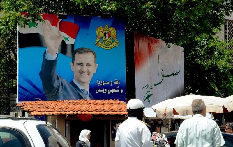 Syrian citizens walking past an election campaign billboard with photo of Syrian President Bashar al-Assad in Damascus, Syria, 11 May 2014. EPA/SANA HANDOUT