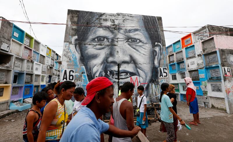 Filipinos pass by a mural on the wall of apartment-type crypts as they visit a public cemetery to honour their departed loved ones in the traditional observance of All Saints Day in Manila, Philippines. Bullit Marquez / AP Photo
