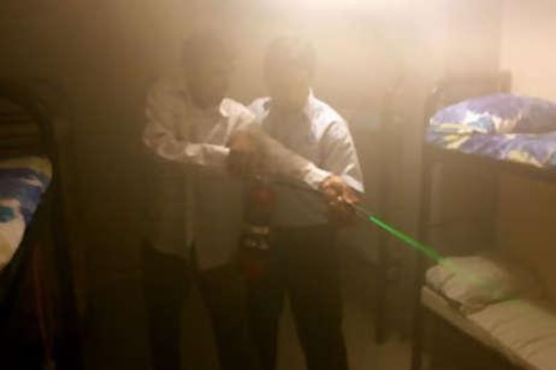 Trainees take aim and guide the green laser beam of a fire extinguisher at the source of a potential fire as part of a series of safety exercises.