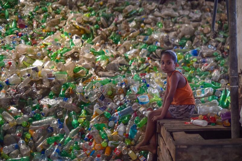 A girls sits next to a pile of used plastic bottles in a recycling factory in Dhaka, Bangladesh, on May 5. AFP