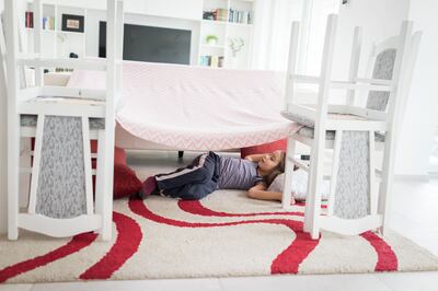 Child in a pillows and chairs fort making home. Getty Images