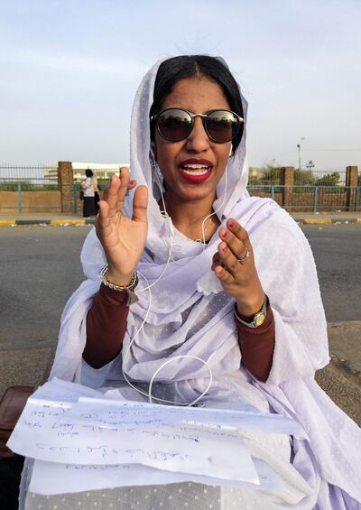 Alaa Salah, a Sudanese woman propelled to internet fame earlier this week after clips went viral of her leading powerful protest chants against President Omar al-Bashir, gestures as she sits during a demonstration in front of the military headquarters in the capital Khartoum on April 10, 2019. In the clips and photos, the elegant Salah stands atop a car wearing a long white headscarf and skirt as she sings and works the crowd, her golden full-moon earings reflecting light from the fading sunset and a sea of camera phones surrounding her. Dubbed online as "Kandaka", or Nubian queen, she has become a symbol of the protests which she says have traditionally had a female backbone in Sudan.
 / AFP / -
