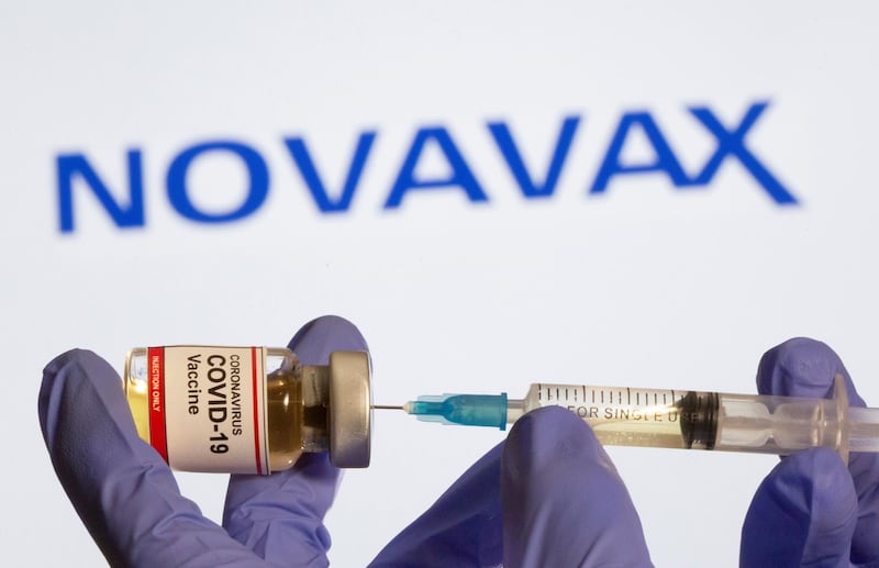 FILE PHOTO: A woman holds a small bottle labeled with a "Coronavirus COVID-19 Vaccine" sticker and a medical syringe in front of displayed Novavax logo in this illustration taken, October 30, 2020. REUTERS/Dado Ruvic/File Photo